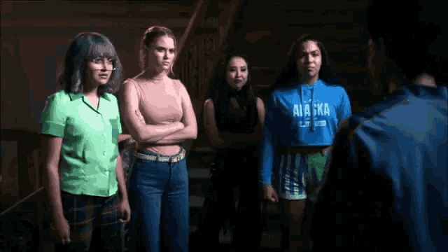 a group of girls standing next to each other with one wearing a blue alaska sweatshirt