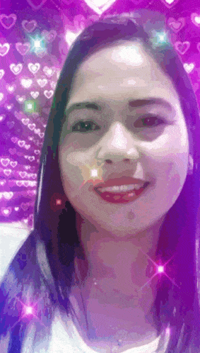 a woman is smiling in front of a pink background with hearts