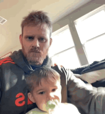 a man with a beard is holding a baby with a pacifier in its mouth .