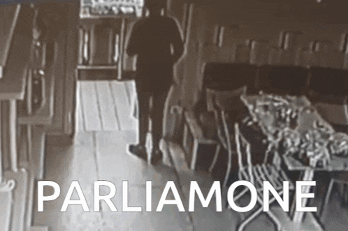a blurred image of a man walking in a room with the words parliamone written on the bottom