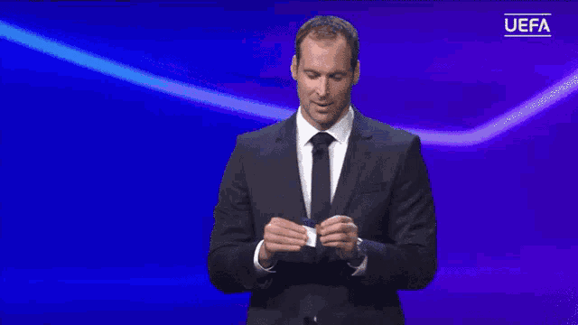 a man in a suit and tie is holding up a card with the letter f on it