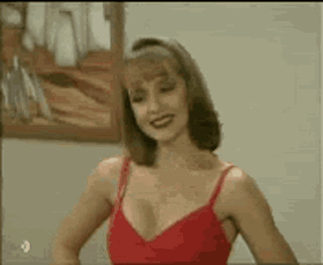a woman in a red bra is standing in front of a picture .