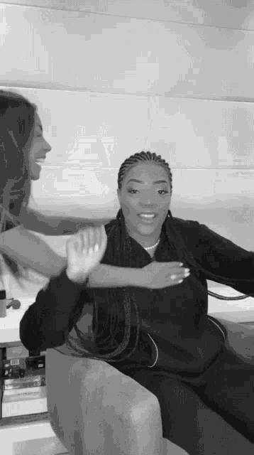 two women are sitting on a couch giving each other a high five