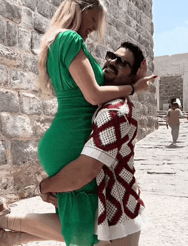 a woman in a green dress is being lifted by a man in a red and white shirt