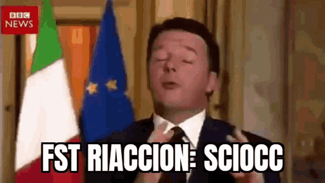 a man in a suit and tie is standing in front of a flag and says fst riaccion sciocco .