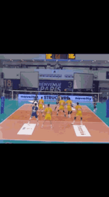 a volleyball game is being played in a stadium with a sign that says bienvenue paris on it