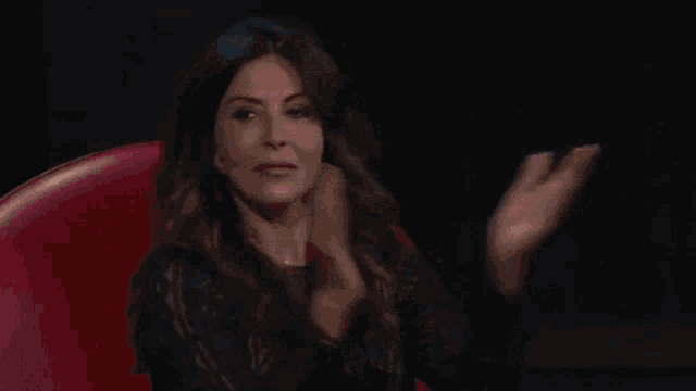 a woman is sitting in a red chair applauding .
