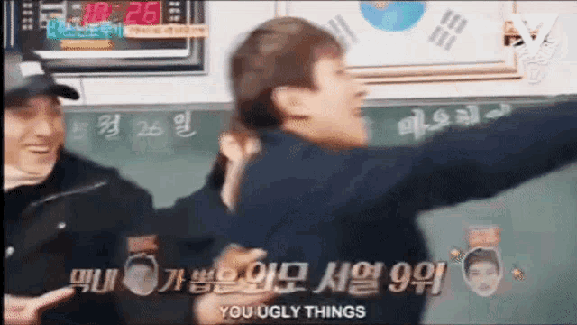 a group of people are standing in front of a blackboard with the words you ugly things written on it .