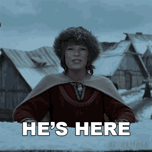 a boy in a fur hat says he 's here in front of snowy houses