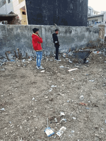 a man in a red jacket is standing in a dirt area