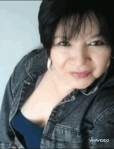 a woman wearing a denim jacket and a blue shirt is smiling for the camera .