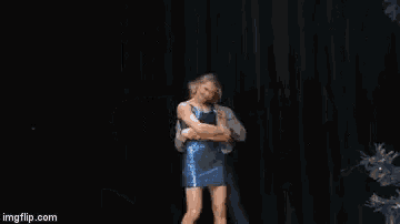 a man and a woman are dancing on a stage . the woman is wearing a blue dress .