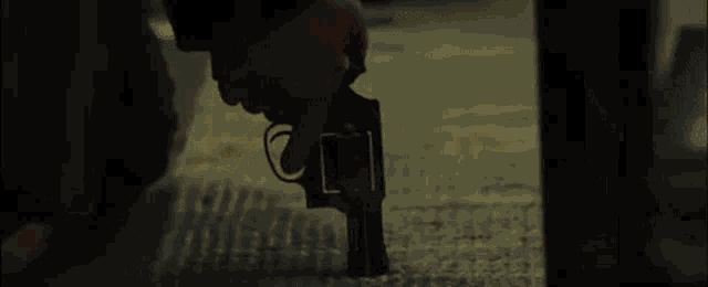 a person is holding a gun in their hand and pointing it at something .