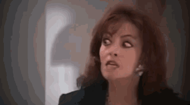 a woman with red hair is making a funny face while standing in a room .