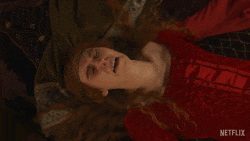 a woman in a red dress is laying on a bed with netflix written on the bottom right