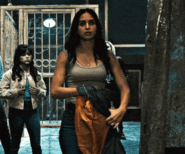 a woman in a tank top is standing next to another woman in jeans