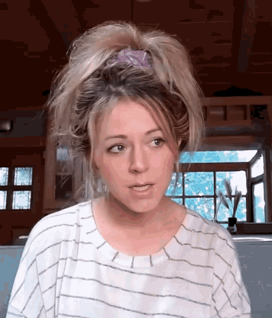 a woman wearing a striped shirt and a ponytail looks at the camera