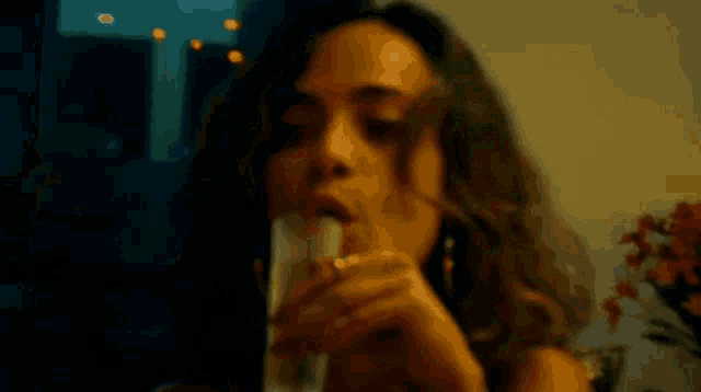 a woman is smoking a cigarette while holding a glass of wine .
