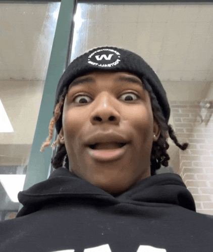 a young man wearing a black beanie with the letter w on it