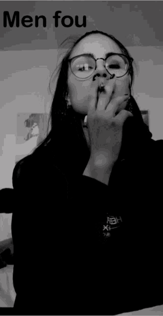 a black and white photo of a woman wearing glasses and a black shirt that says men fou on it