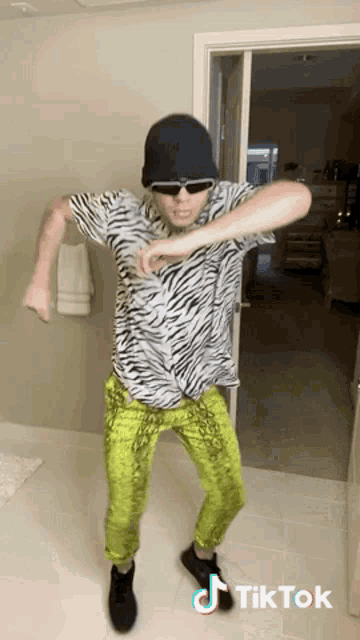 a man in a zebra print shirt and neon green pants is dancing on a tiktok video ..