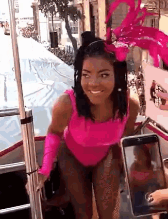 a woman in a pink costume is taking a picture of herself on her phone .