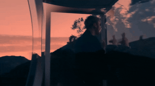 a blurry picture of a man standing in front of a window at sunset