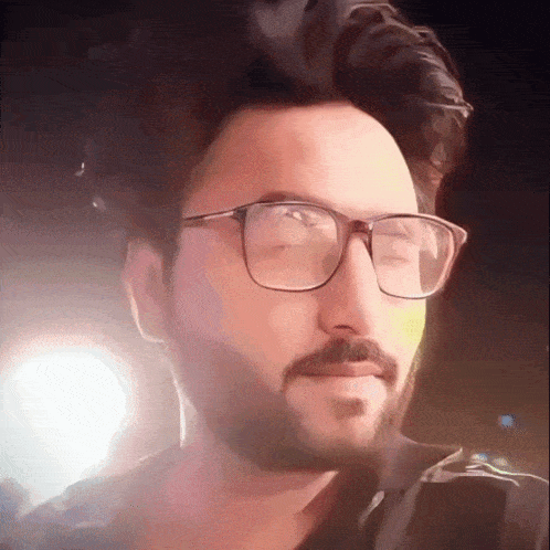 a man with glasses and a beard is smiling at the camera