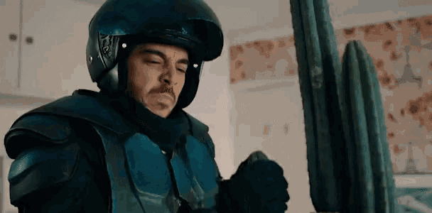 a man wearing a helmet and armor holds a cactus in his hands