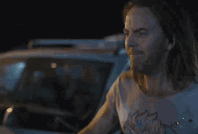 a man with long hair stands in front of a car with the words no don t pull this shit with