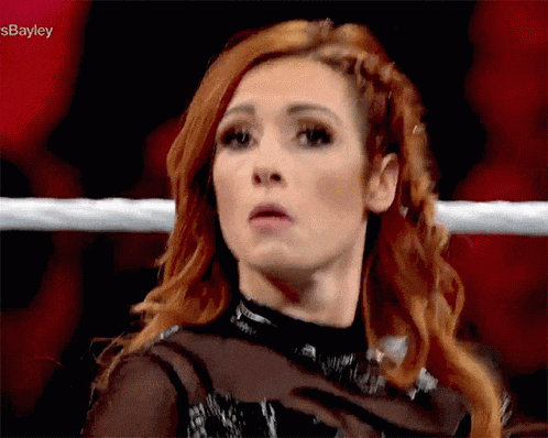a woman with red hair is standing in a wrestling ring and making a face .