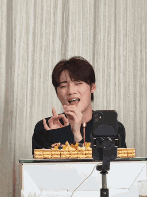 a man eating a cake with a candle in front of a phone that says " congratulations "
