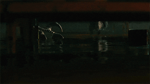 a person is standing in a dark room with a claw on their hand