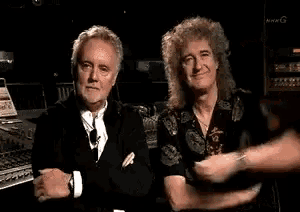 two men are standing next to each other in a dark room .