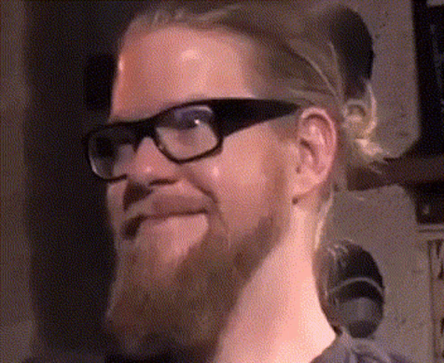 a man with glasses and a beard is making a funny face