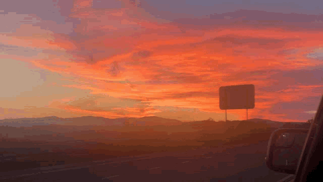 a sunset over a highway with mountains in the background