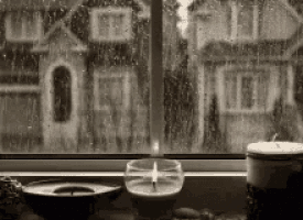 a black and white photo of a window with a candle and a candle holder on a table .