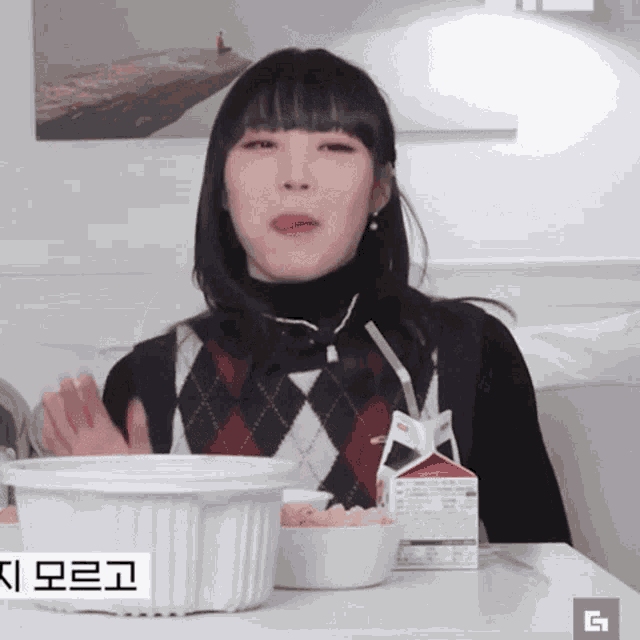 a woman sitting at a table with a box of milk and a bowl of food