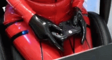 a woman in a red latex suit is holding a video game controller in her hands .