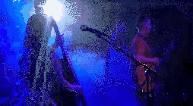 a man playing a guitar in front of a blue light