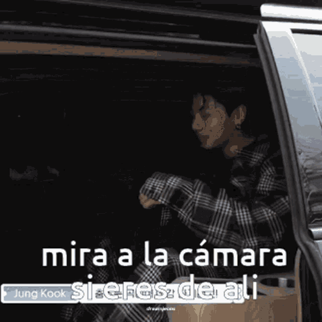 a man in a plaid shirt is sitting in the back of a car with the caption mira a la camara
