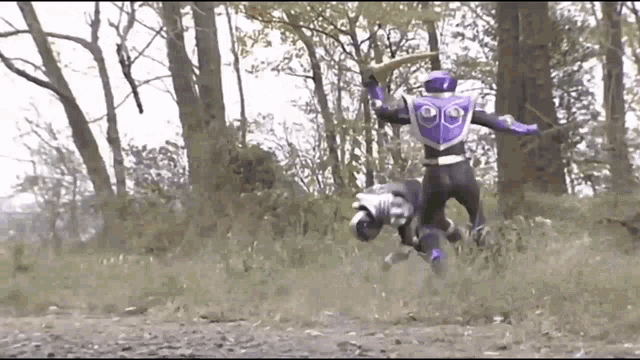 a purple and black superhero is fighting another superhero in a field with trees in the background .