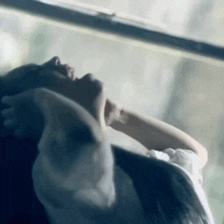 a woman is laying down in front of a window with her head down .