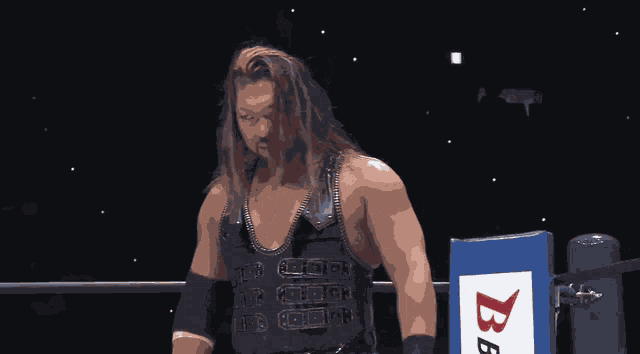a wrestler is standing in front of a bb logo