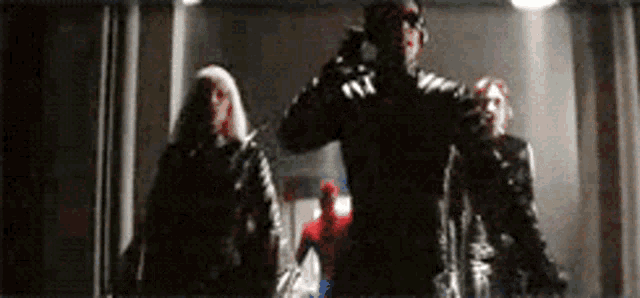 a group of superheros are walking through a dark hallway .