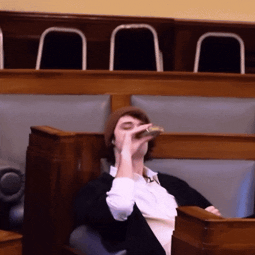 a man sitting in a row drinking from a bottle