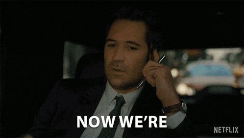 a man in a suit and tie is talking on a cell phone with the words getting somewhere netflix below him