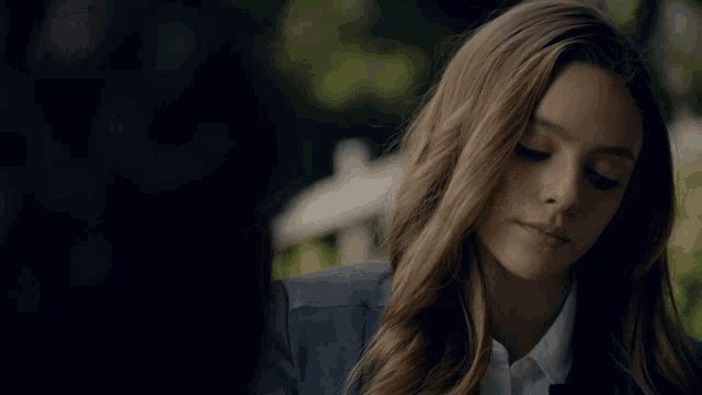 a woman with long hair is wearing a blue jacket