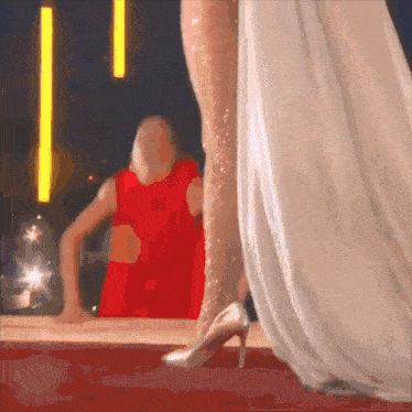 a woman in a red dress is standing next to a woman in a white dress on a red carpet
