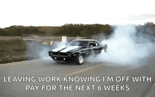 a black car is drifting down a road with smoke coming out of its tires .